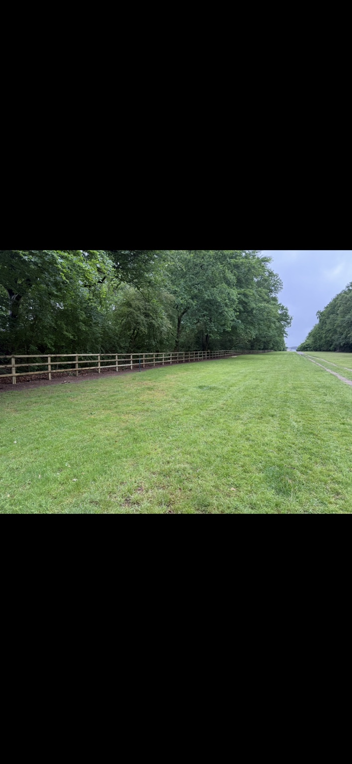 Post and rail fencing across open grounds by Cartwright Fencing Company